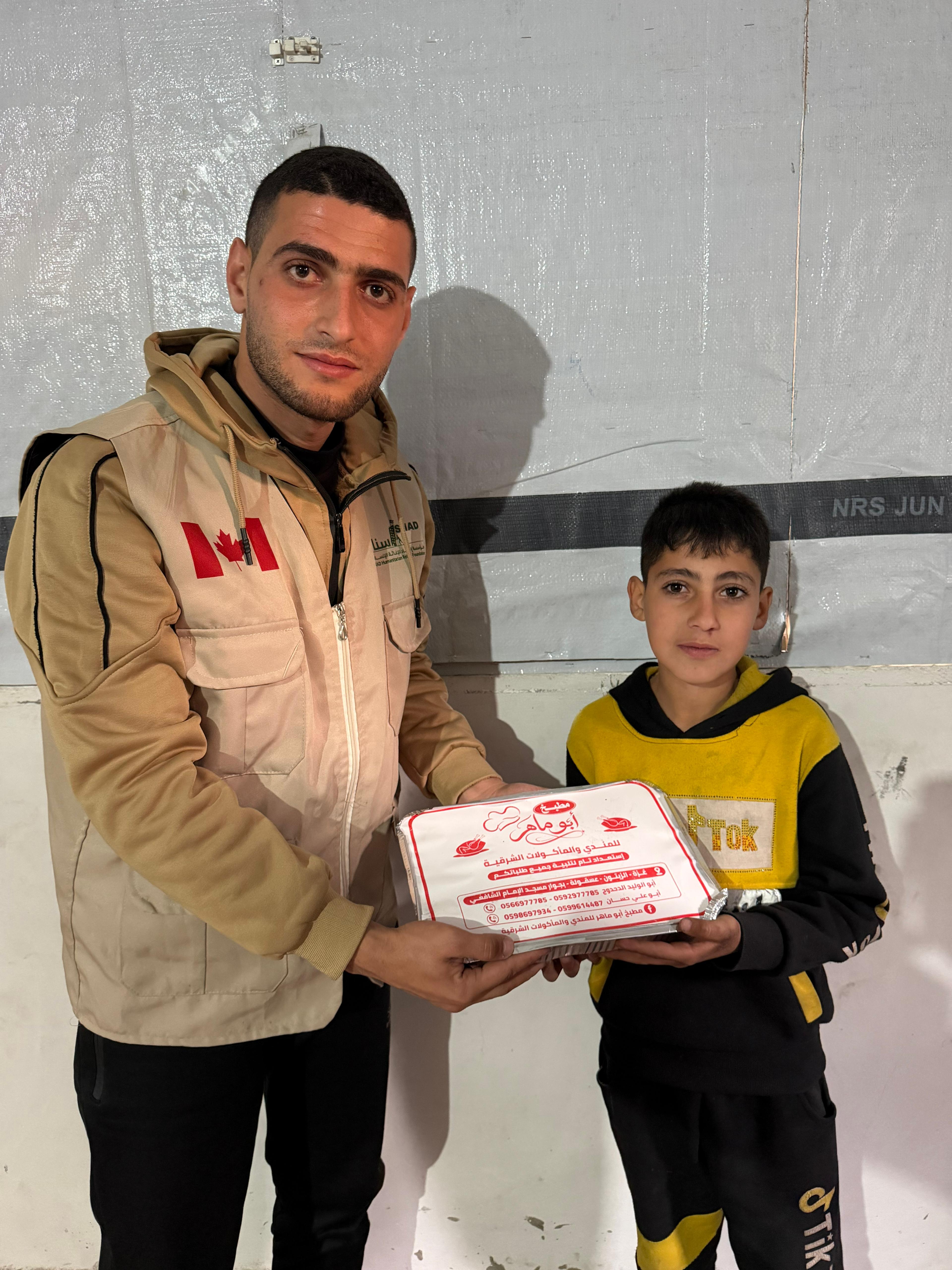 Isnad volunteer distributing food packages to a child in Gaza